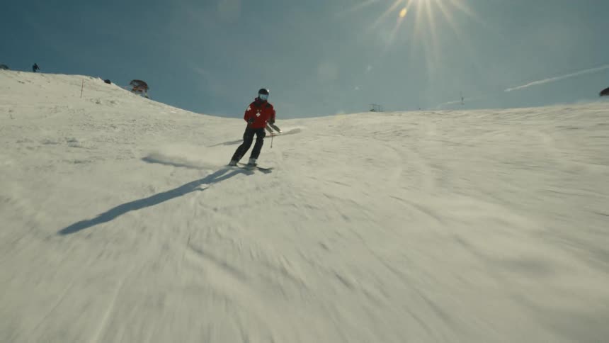 Energetic slow-motion shot of two skiers skillfully carving down a mountain slope in the bright sun