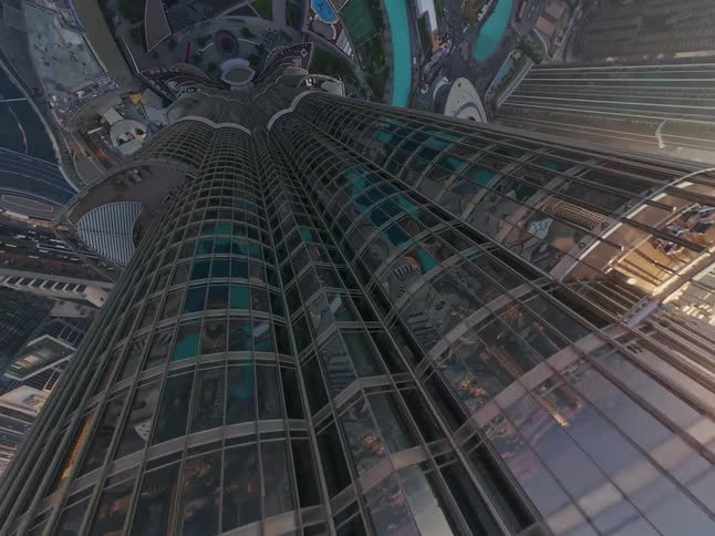 An exhilarating aerial perspective tilts down the side of the magnificent Burj Khalifa, showcasing the sprawling Dubai cityscape