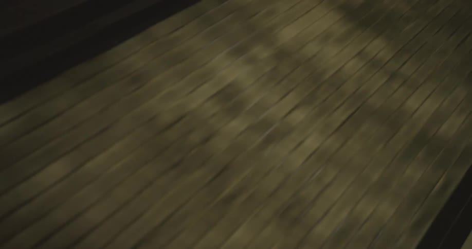 A blurry, fast-moving first-person perspective shot of someone running down a dark, paved path at night