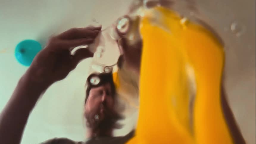 Slow motion POV shot of a man cracking a raw egg directly over the camera lens