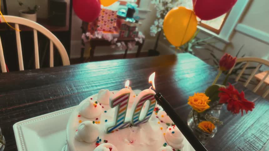 A slow-motion, first-person view of lighting the number 10 candles on a birthday cake at a decorated party