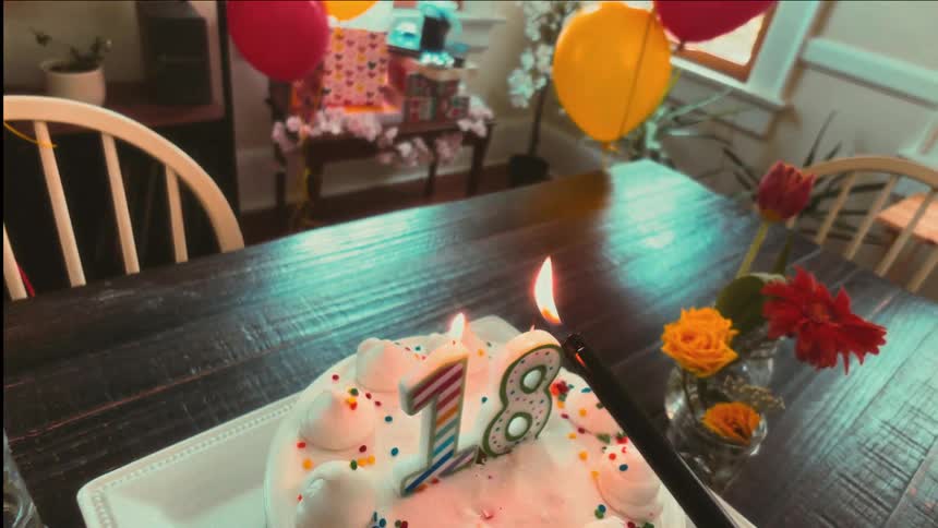 A slow-motion, stylized point-of-view shot of lighting the number 18 candles on a birthday cake