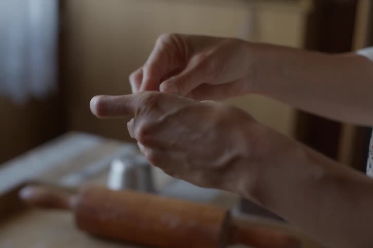A close-up in slow motion shows a baker's hands meticulously pinching and sealing the edges of a homemade pastry