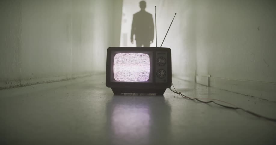A mysterious silhouetted man walks down a long, dark hallway, leaving behind an old television set displaying static on the floor