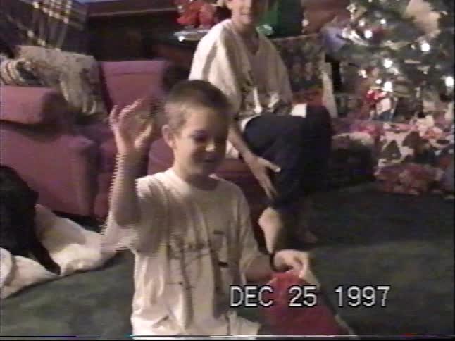 Vintage VHS footage of a young boy happily looking through his stocking on Christmas morning in 1997