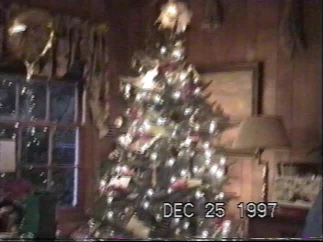 Vintage home video footage shows a beautifully decorated Christmas tree with presents underneath on Christmas day in 1997