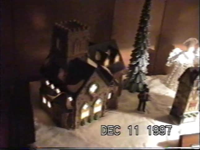 Cozy vintage home video footage pans across a miniature, lighted Christmas village scene from 1997
