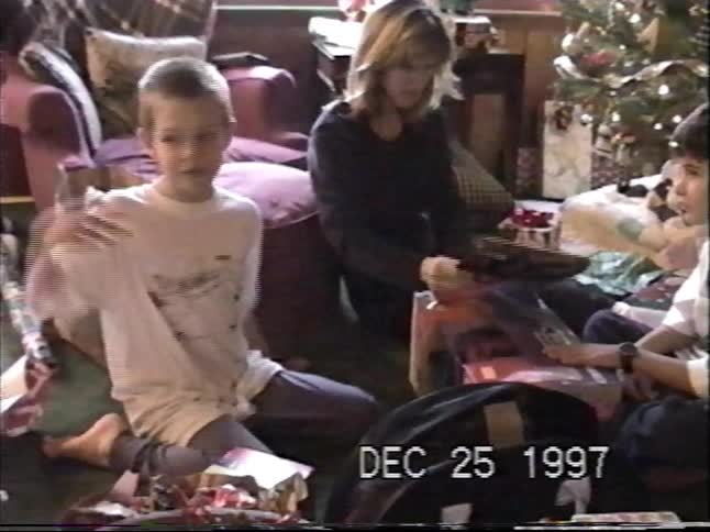 Vintage VHS home video from 1997 captures kids opening presents together on Christmas morning
