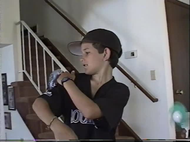 A young boy holds a pet parakeet on his hand and lets it crawl up his arm and fly away inside a home