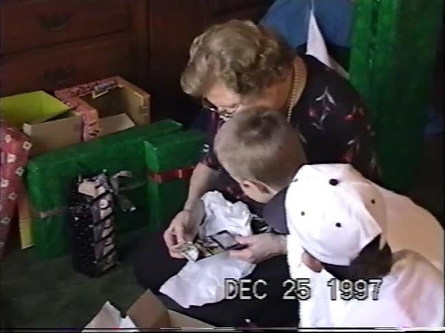Vintage 1997 home video of a grandmother opening a Christmas present while her two grandsons watch