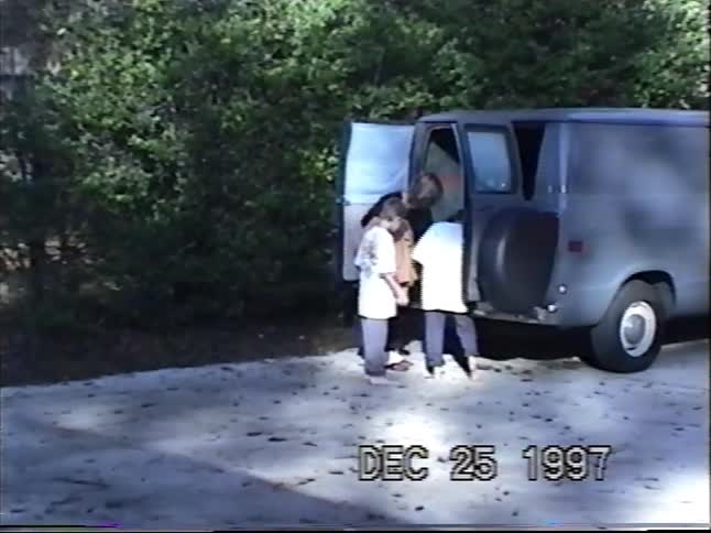 Vintage VHS footage from Christmas 1997 shows a mother and her two sons getting out of their van in the driveway
