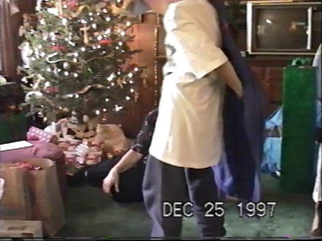 A young boy excitedly opens a Christmas present in 1997 and is thrilled to receive a new blue robe which he immediately tries on