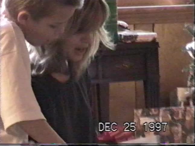 A mother and her two sons open Christmas presents together in a nostalgic home video from 1997