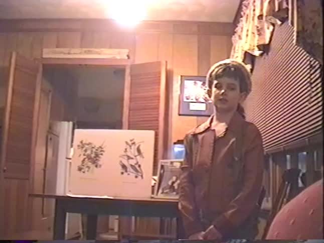 Nostalgic home video footage from the 1990s shows a young girl in a frontiersman costume giving a school presentation on botany