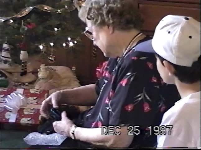 A vintage 1997 home video shows a grandmother and her grandson opening Christmas presents by the tree
