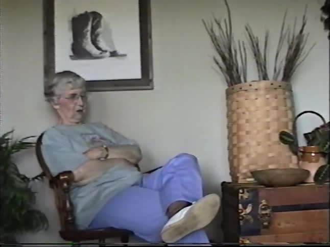 Nostalgic home video footage shows a multi-generational family gathering and talking in a cozy living room setting