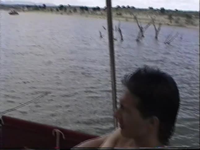 Vintage VHS home movie footage shows a family relaxing together on a boat trip on a lake