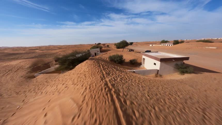 An exhilarating FPV drone flight explores a derelict village being slowly consumed by desert sand dunes