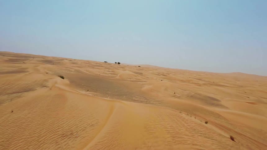 A dynamic first-person view drone flight soaring low over the vast, rippling golden sand dunes of an endless desert