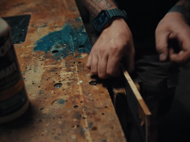 Craftsman meticulously applies small wood tiles for an intricate inlay on a piece of wood in a workshop