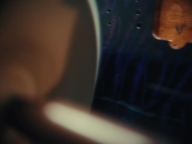 An artistic macro close-up reveals the stunning flamed wood grain of a custom-built guitar body
