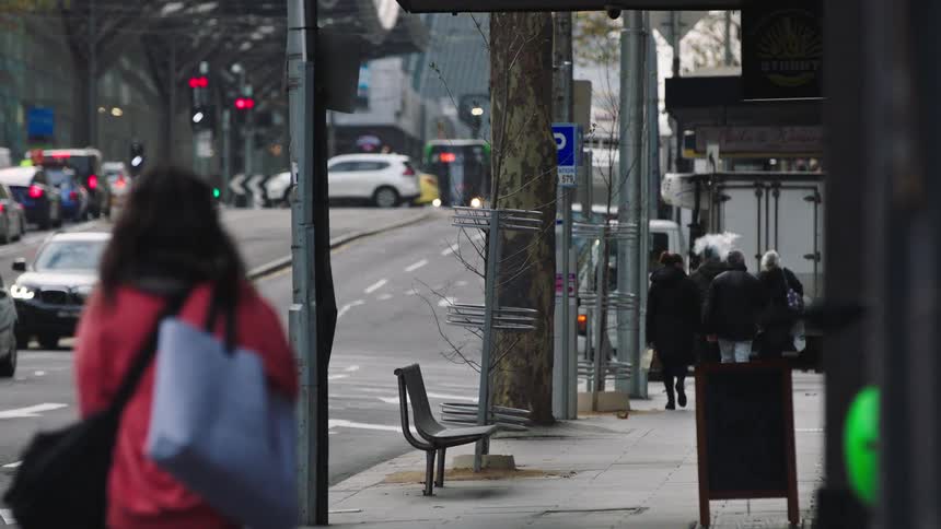 Slow motion shot of people walking on a sidewalk in a busy city with traffic in the background