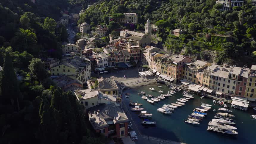 Stunning aerial view slowly approaching the famous harbor of Portofino, Italy, showcasing the vibrant coastal town and luxury boats