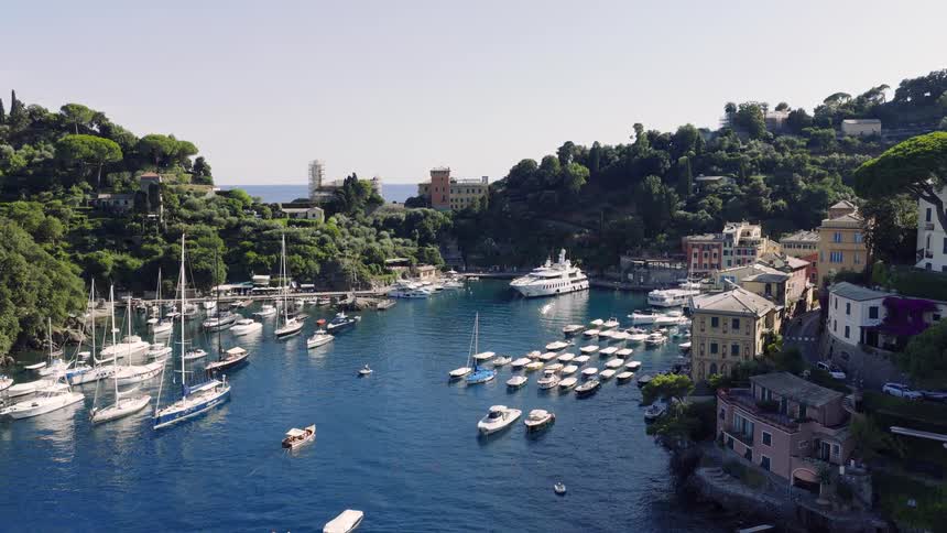 Slowly flying over the beautiful blue Mediterranean waters towards the iconic and luxurious harbor of Portofino, Italy