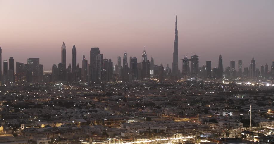 Lights twinkle in a city at sunset