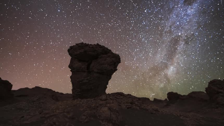 A holy grail timelapse shows the transition from a sunny day to a starry night with the Milky Way and moonrise over a unique rock formation in the Atacama Desert