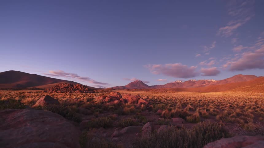 Stunning day-to-night timelapse shows the sun setting over a rocky desert valley and mountains, revealing a spectacular starry night sky