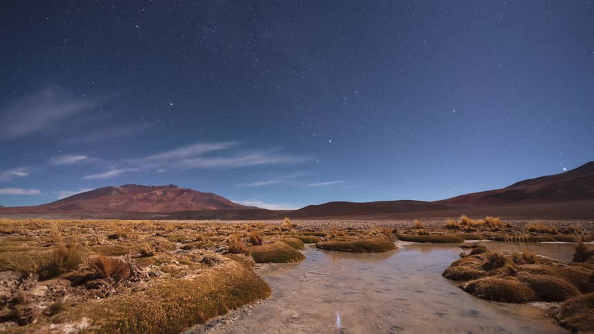 A breathtaking night time-lapse captures the starry sky and moonrise over a tranquil mountain desert landscape