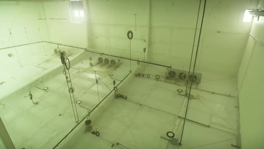 A slow zoom out from a stained concrete ceiling reveals a vast, empty, and eerie industrial testing room