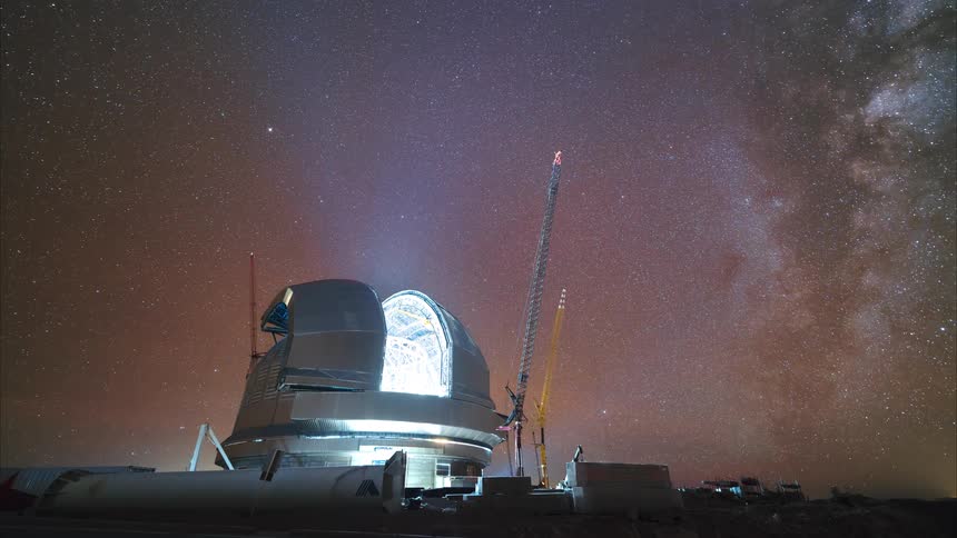 A stunning night-to-day timelapse shows the Milky Way galaxy rising over a large astronomical observatory under construction before the sun rises