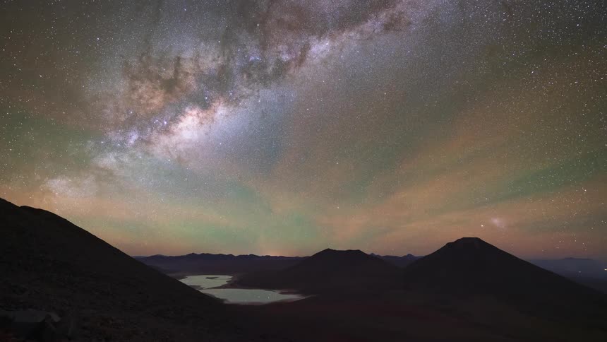 An epic holy grail time-lapse captures a full cycle from sunset to sunrise over volcanic peaks in the desert, revealing a spectacular starry night with the Milky Way