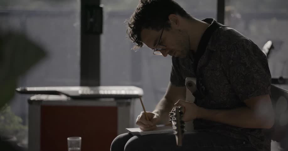 A man is composing a song on the guitar