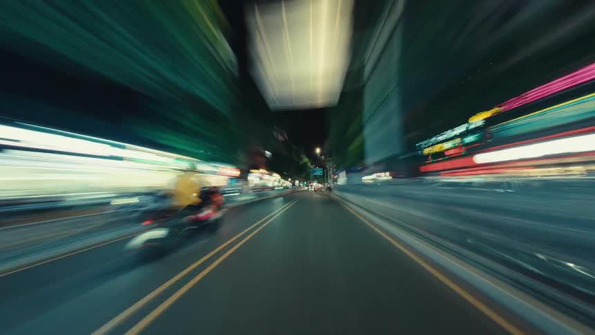 A high-speed first-person hyper-lapse journeys down a city street at night, with storefront lights creating colorful motion-blurred streaks