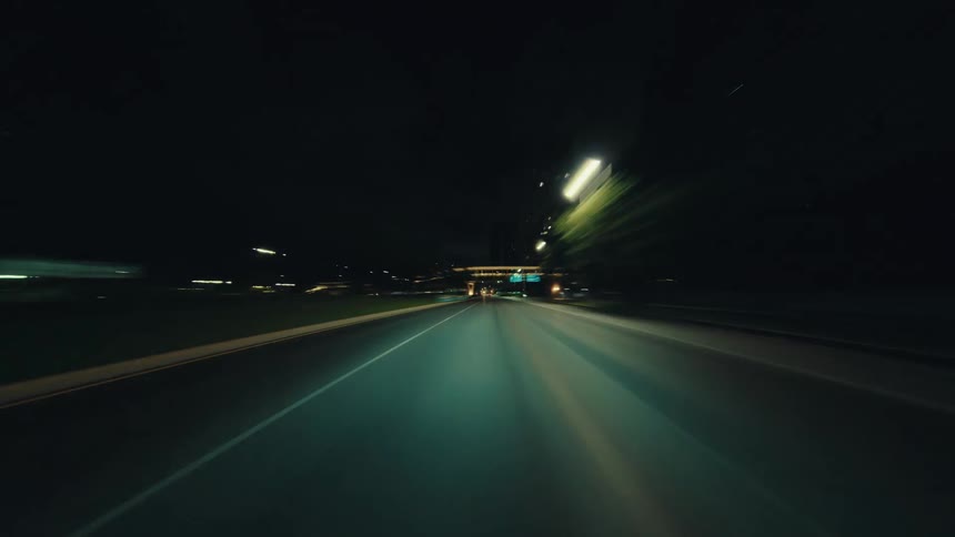 A surreal first-person hyperlapse of driving through a city highway at night, where streetlights and traffic blur into long streaks of light