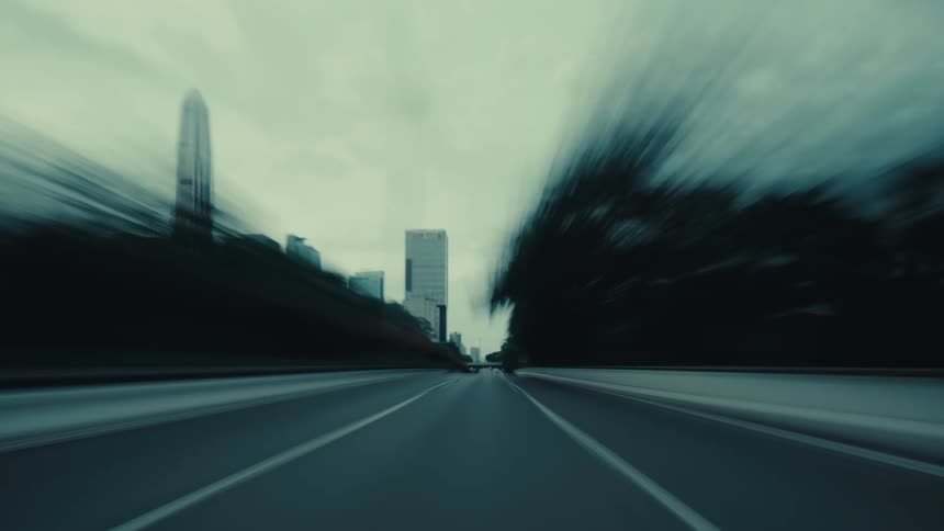 A moody, first-person hyper-lapse of driving at high speed down an empty highway through a modern city