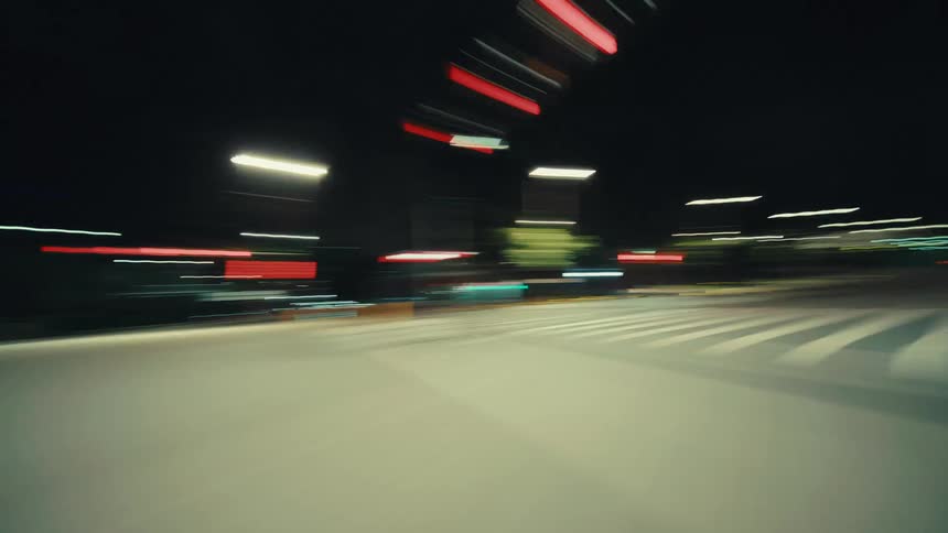 A futuristic point-of-view timelapse driving through a modern tunnel and onto city streets at night