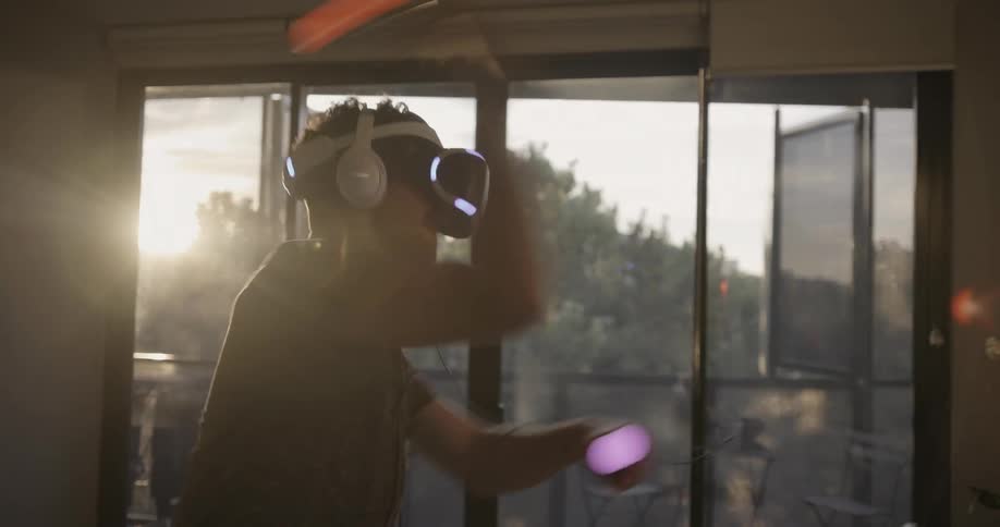 A man plays with a virtual reality machine in front of a sunny window