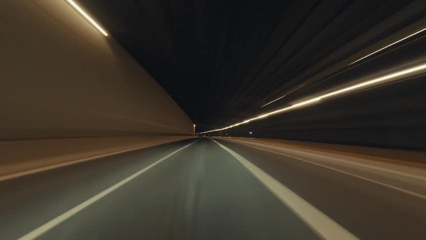 A fast-paced hyperlapse from a driver's perspective captures the mesmerizing light trails on a highway and through tunnels at night