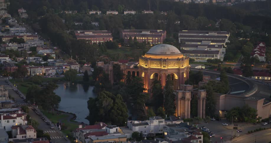 A stunning aerial view of the illuminated Palace of Fine Arts in San Francisco at twilight, slowly revealing the surrounding scenic neighborhood