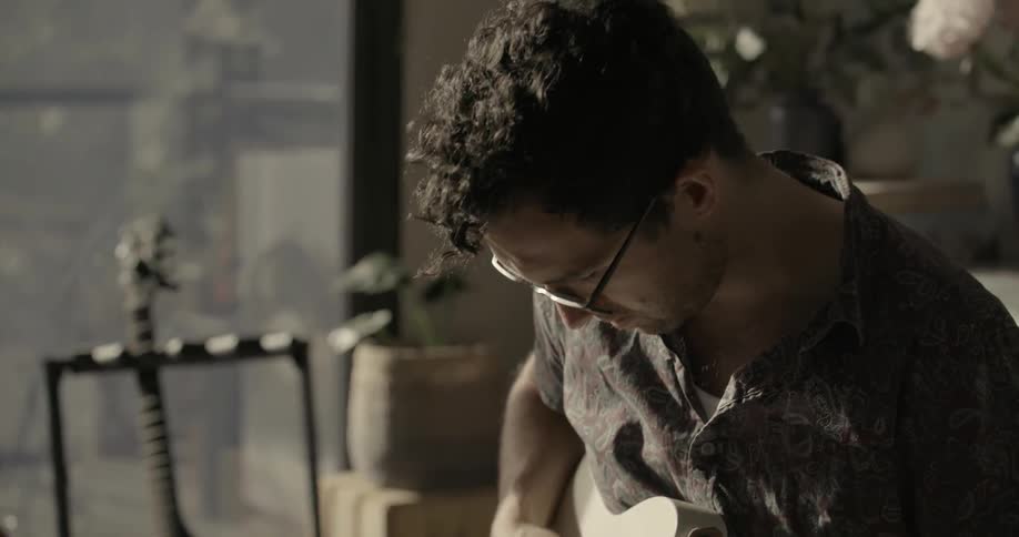 A man has a notebook on his lap, and he is playing guitar