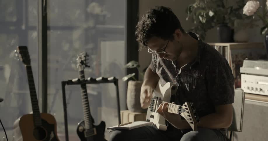 Man playing a guitar indoors while seated