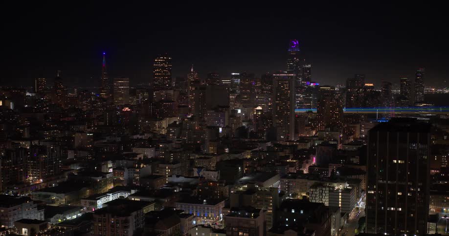 A breathtaking wide shot of the San Francisco skyline illuminated by vibrant city lights against the dark night sky