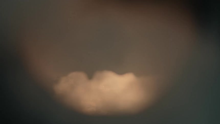 A soft-focus abstract shot captures lightning flashing dramatically inside a distant, turbulent storm cloud