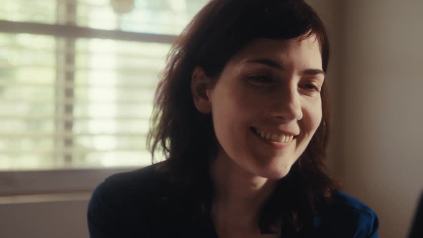 Close up of a woman looking at her smartphone as her expression softens and turns into a happy smile