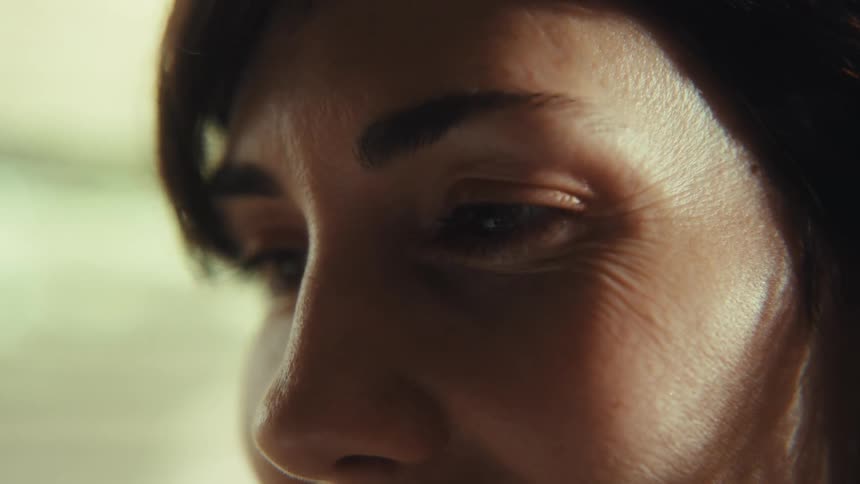 Extreme close-up with a slow rack focus reveals the gentle smile and eye wrinkles of a mature woman