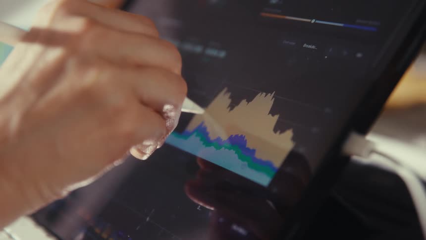 A businesswoman analyzes financial data on a tablet with a digital stylus, tracking the market graph